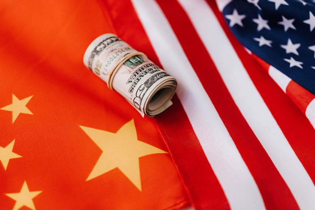 A rolled US dollar placed on overlapping USA and China flags, symbolizing international trade relations.